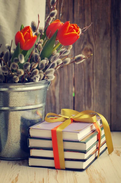 Bücher und ein Frühlingsstrauß aus Tulpen und Zweigen einer Weide — Stockfoto