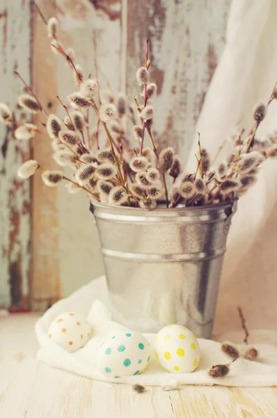 Easter eggs with a bouquet of spring branches of a willow in a bucket — Stock Photo, Image