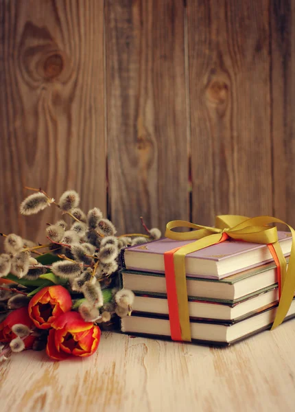 Books and a spring bouquet of tulips and branches of a willow — Stock Photo, Image