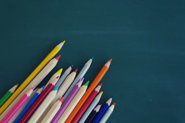 Цветные деревянные карандаши против зеленой доски . — стоковое фото