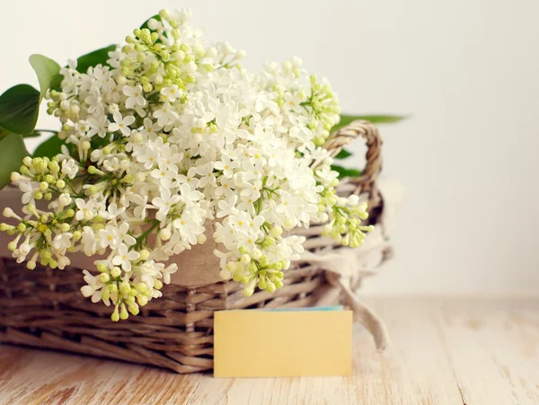 Bir ahşap yüzeyde bir sepette beyaz leylak buket. 