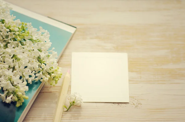 Boeket van een witte Lila op het open boek en de witte lege kaart voor een inscriptie. — Stockfoto