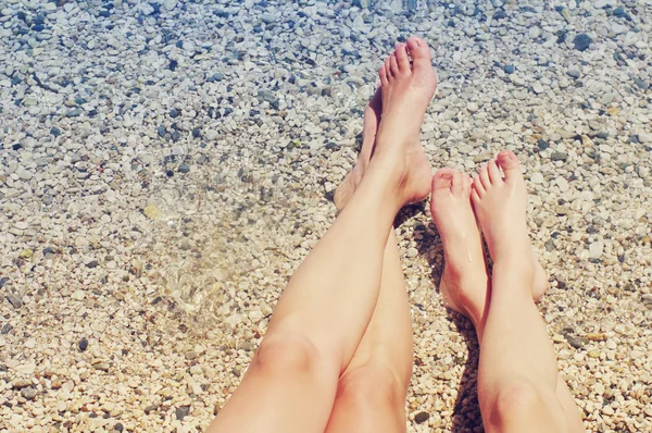 Los pies femeninos y infantiles en la playa contra el mar en el día veraniego soleado . —  Fotos de Stock