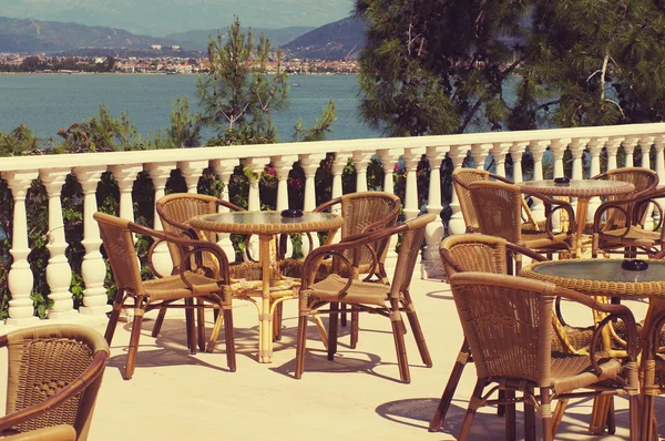 Empty tables and chairs on the coast against the sea and mountains