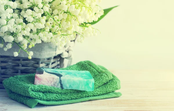 Natural soap of handwork, towel, and spring flowers of a lily of the valley in a wattled basket — Stock Photo, Image