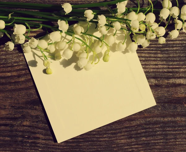 Bouquet of lilies of the valley and the empty white card for an inscription — Stock Photo, Image