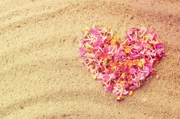 Heart from tropical pink flowers on sand. — Stock Photo, Image