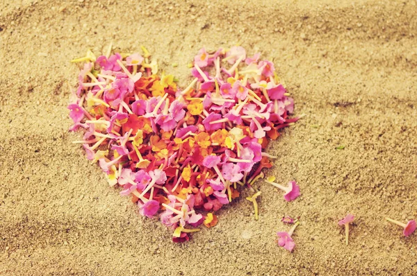 Heart from tropical pink flowers on sand. — Stock Photo, Image