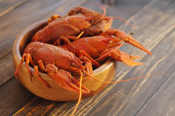 Gekookte crawfishes in een ronde houten plaat op een houten achtergrond — Stockfoto