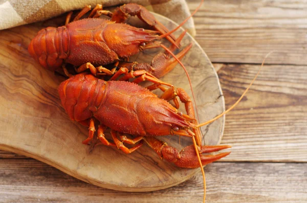 Peces cangrejos cocidos sobre una tabla de madera sobre un fondo de madera — Foto de Stock