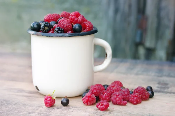 Fresas bayas jugosas, frambuesas, grosellas, moras, grosellas en una taza de hierro blanco —  Fotos de Stock