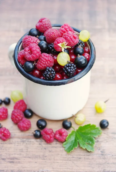 Fresas bayas jugosas, frambuesas, grosellas, moras, grosellas en una taza de hierro blanco —  Fotos de Stock