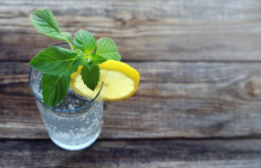 Cam soğuk köpüklü su, bir dilim limon ve nane taze yeşillik ile 