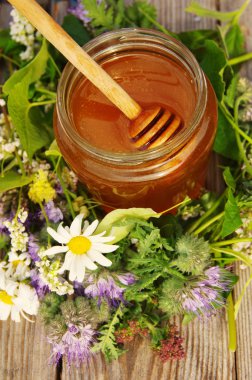 Çiçekler bir cam kavanoza bir ahşap yüzeyde melliferous otlar tatlım. 