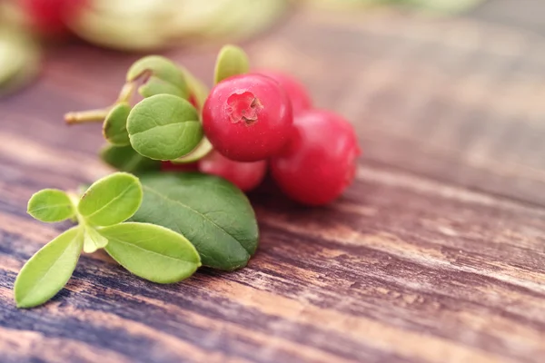 Bacche succose di cowberry, mirtilli rossi, mirtilli rossi su uno sfondo di legno — Foto Stock