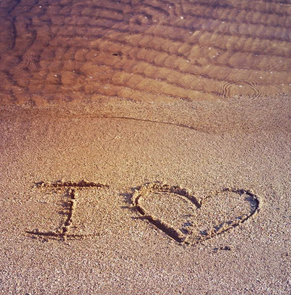 Tekst "I love" op de zand op een strand worden getekend — Stockfoto