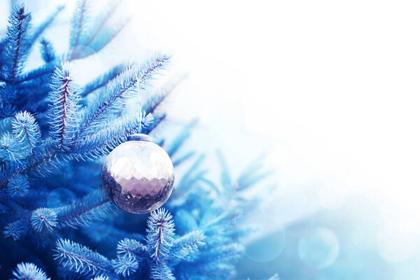 Рождественский стеклянный шар на ветке елки, крупным планом, мягким выборочным фокусом. Голубой рождественский фон с мячом, пространство для копирования