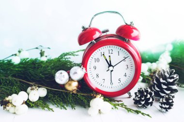 Red vintage alarm clock showing the time 23:55 near a window with a Christmas tree decor, soft selective focus. Preparing for the new year, christmas
