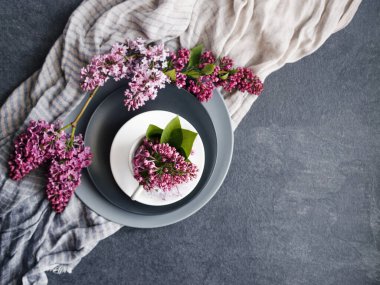 Bahar festivali arka planı, mor leylak çiçekleri, yuvarlak gri tabakalar ve ince kumaşlar, üst manzara, kopyalama alanı.