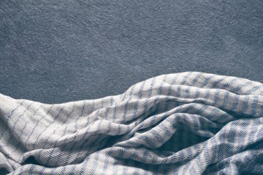 Koyu masa yüzeyinde mavi-gri pamuklu kumaş, peçete, çizgili masa örtüsü veya eşarbı olan soyut arkaplan, yumuşak odak, kopyalama alanı