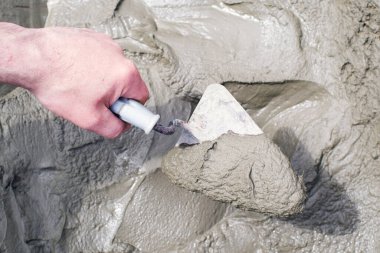 Erkek eli çimento harcı yoğuruyor, malayla, yakın plan. İnşaat çalışmaları.