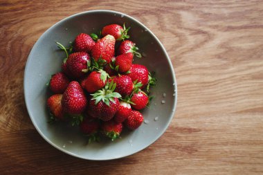 Taze sulu çilekler yeşil bir tabakta ahşap bir masada yakın plan, kopyalama alanı, üst görünüm