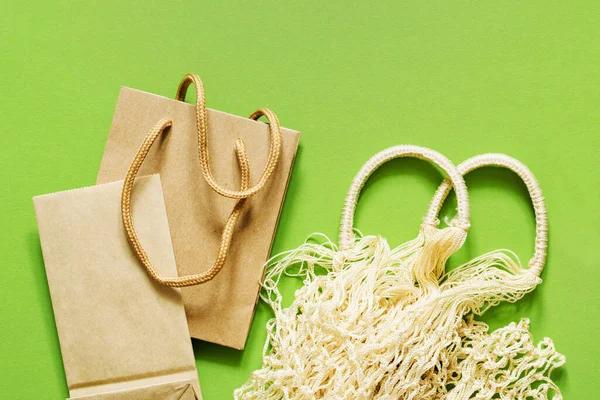 Reusable shopping bag and paper packaging on a green background close-up, top view. No plastic, no waste, biodegradable packaging. Environment protection