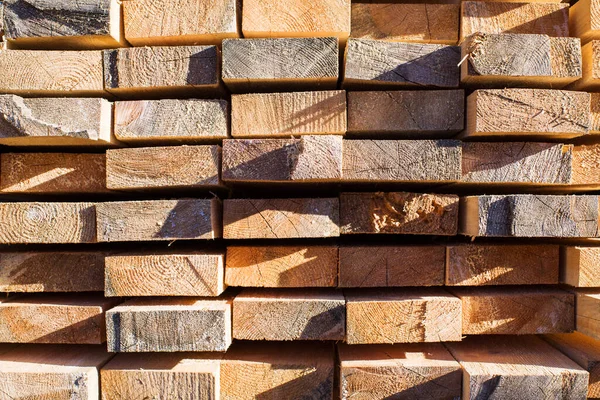 Tahta odunların arka planı, yakın plan. Tahtanın sonundaki yüzey. Yığılmış kereste, kereste, ahşap işçiliği