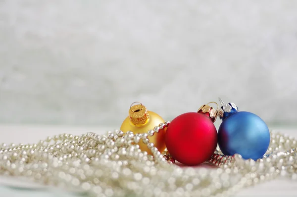 Três bolas de Ano Novo multicores em grinaldas brilhantes — Fotografia de Stock