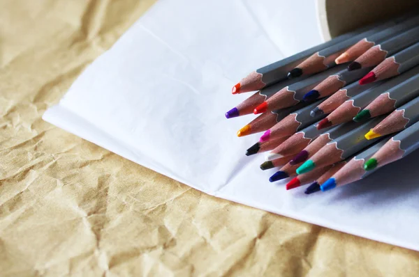 Кольорові олівці на білому і жовтому зім'ятому папері — стокове фото