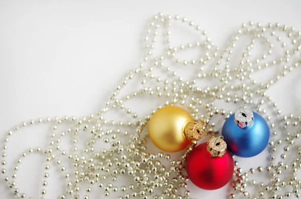 Três bolas de Ano Novo multicores em grinaldas brilhantes — Fotografia de Stock