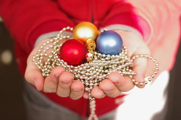 Multi-colored Christmas jewelry in hands — Stock Photo, Image
