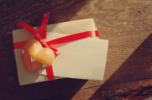 The heart of stone, empty photograph, lie on gift packing with a red bow — Stock Photo, Image