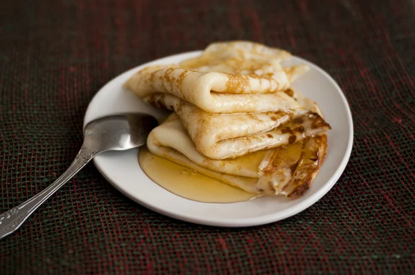Pannkakor med honung på en vit platå — Stockfoto