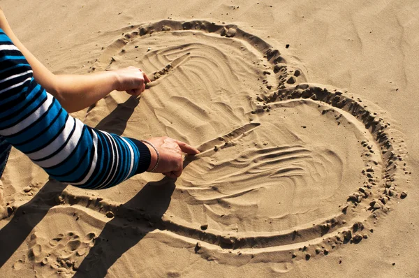 Coeur dessinant sur le sable une jeune paire — Photo