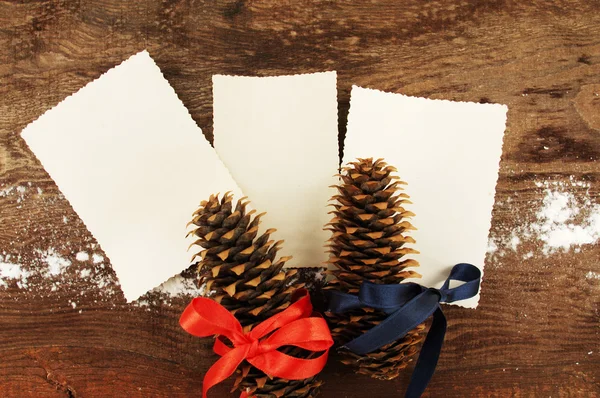 Three empty photographs and two fir cones which are festively decorated with bright tapes — Stock Photo, Image