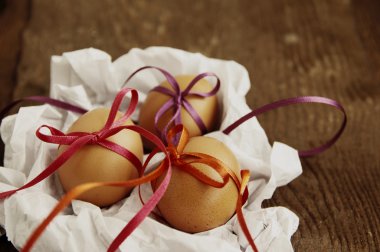 Üç Paskalya yumurta beyaz buruşuk kağıt üzerinde parlak renk bantları