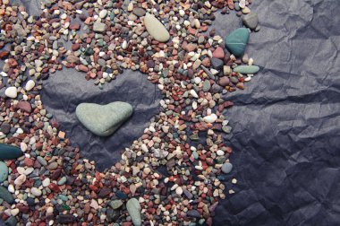 Deniz renk taşlar buruşuk siyah kağıt karşı kalp şeklinde