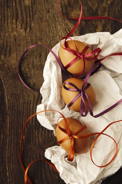 Three Easter eggs with bright color tapes on white crumpled paper — Stock Photo, Image