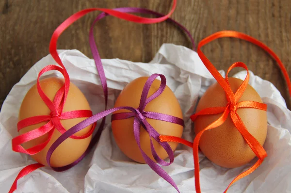 Three Easter eggs with bright color tapes on white crumpled paper — Stock Photo, Image