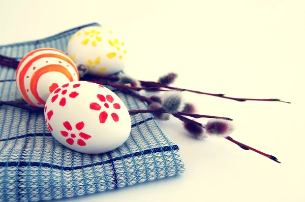 Three Easter eggs with bright drawing with spring branches of a willow on a gray napkin — Stock Photo, Image