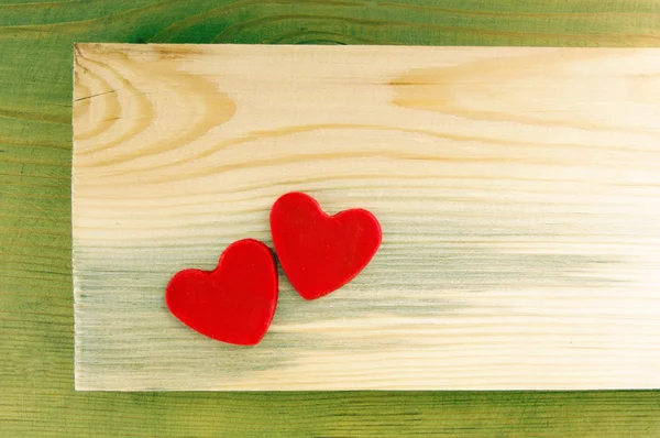 Etkileyici bir yeşil ahşap arka plan üzerinde iki kırmızı kalp. — Stok fotoğraf