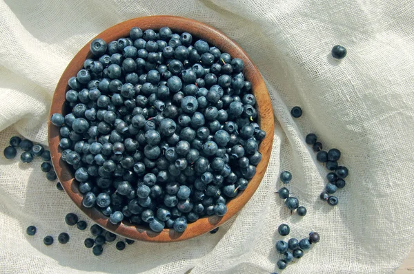 Fresh blueberries in a wooden round plate on a linen cloth — Zdjęcie stockowe
