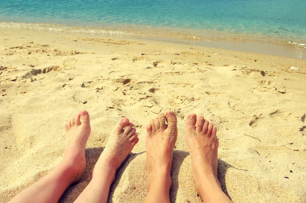 Vrouw en kinderen voeten op een strand tegen de zee in een zonnige zomerdag. Familie rest — Stockfoto