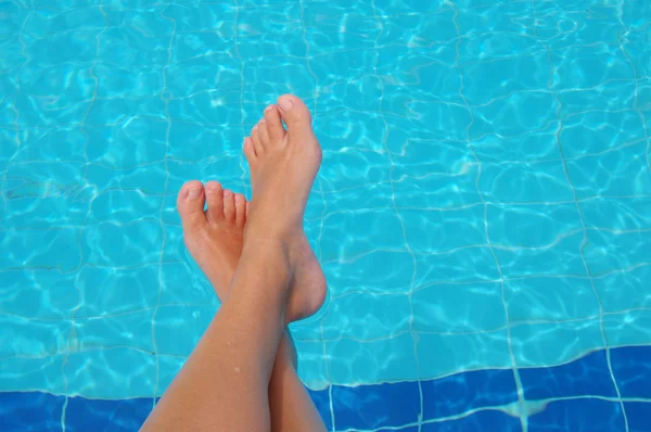 Kobiece stopy przeciwko błękitnej wodzie z basenu. — Zdjęcie stockowe