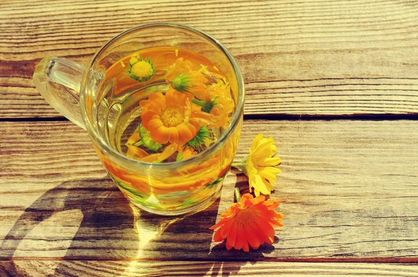 Kadife çiçeği bir şeffaf cam kupa çiçek bitkisel çay. Tıbbi bir calendula çiçeklerin. — Stok fotoğraf