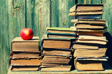 Piles of old books and red apple.