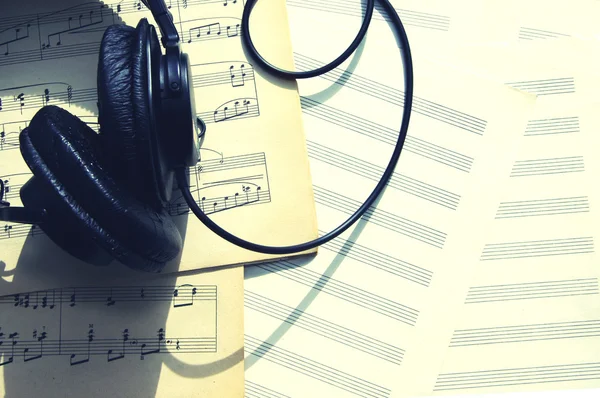 Auriculares negros contra sábanas musicales. Notas y auriculares — Foto de Stock