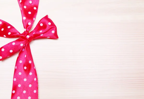 Pink bow in peas on a wooden background. — Stock Photo, Image