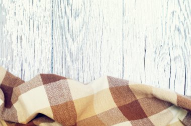 Bir bölümünde eski bir beyaz dokusal ahşap yüzey üzerinde kahverengi katlanmış masa örtüsü.